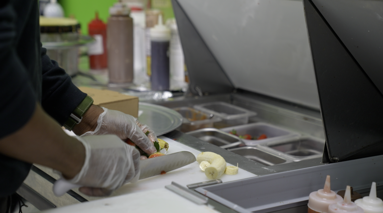 The owner is cutting fruit for some crepes
