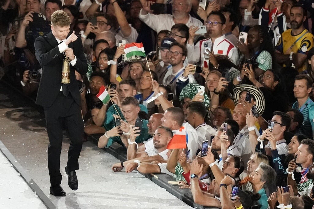 French swimmer Leon Marchand gestures as carries a lantern containing the Olympic flame during the 2024 Summer Olympics closing ceremony.