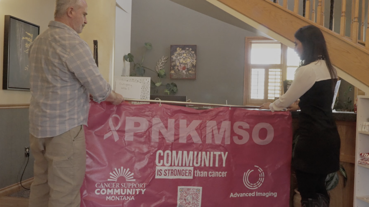 MTN's Cynthia Carranza and Cancer Support Community's Mick Faherty hang up a banner for the PNKMSO campaign.