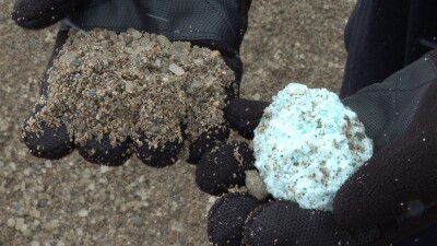 One hand with sand and another with a clump of rock salt