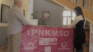 MTN's Cynthia Carranza and Cancer Support Community's Mick Faherty hang up a banner for the PNKMSO campaign.