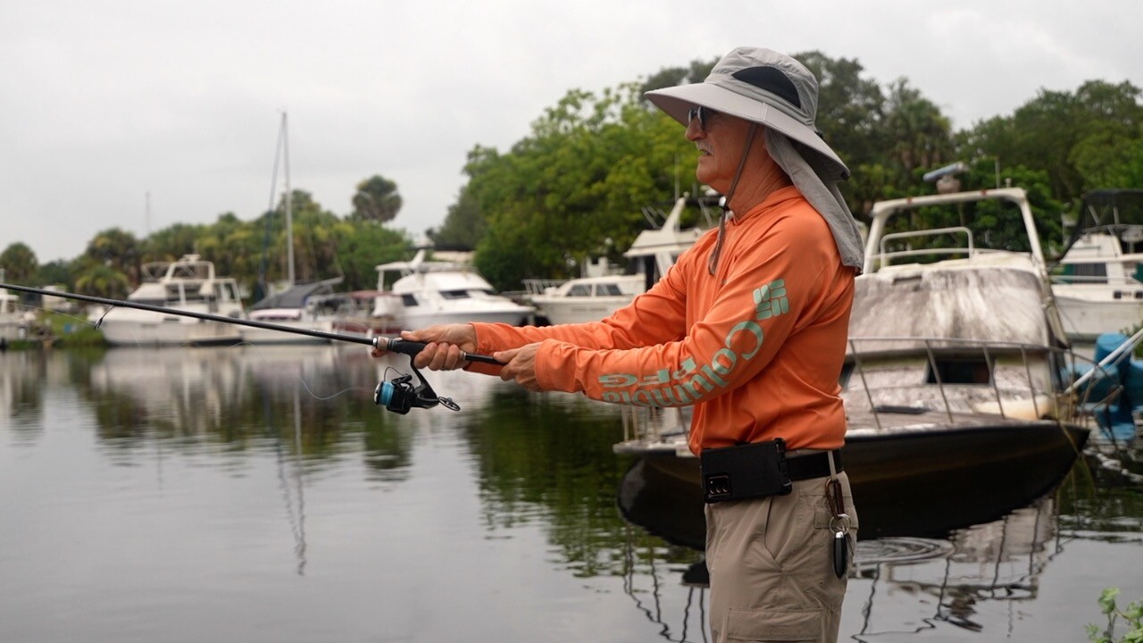 James Anstey casting a line in with the abandoned boats visible behind him.