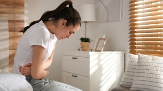 Young,Woman,Suffering,From,Stomach,Ache,On,Bed,At,Home,