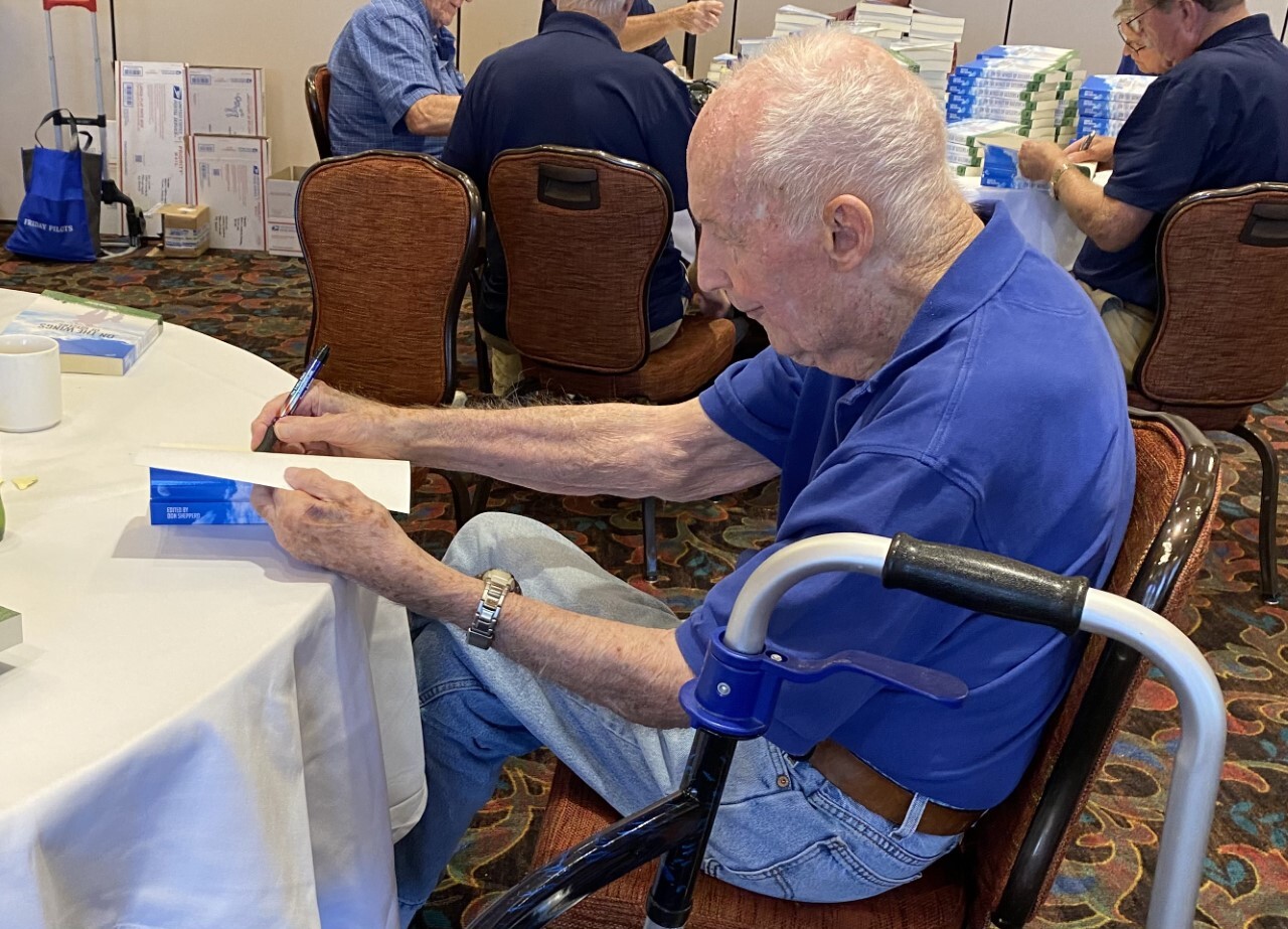 Jim McDivitt autographs a copy of The Friday Pilots new book