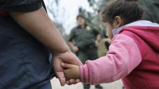 Central American immigrant child with border patrol agent in back ground