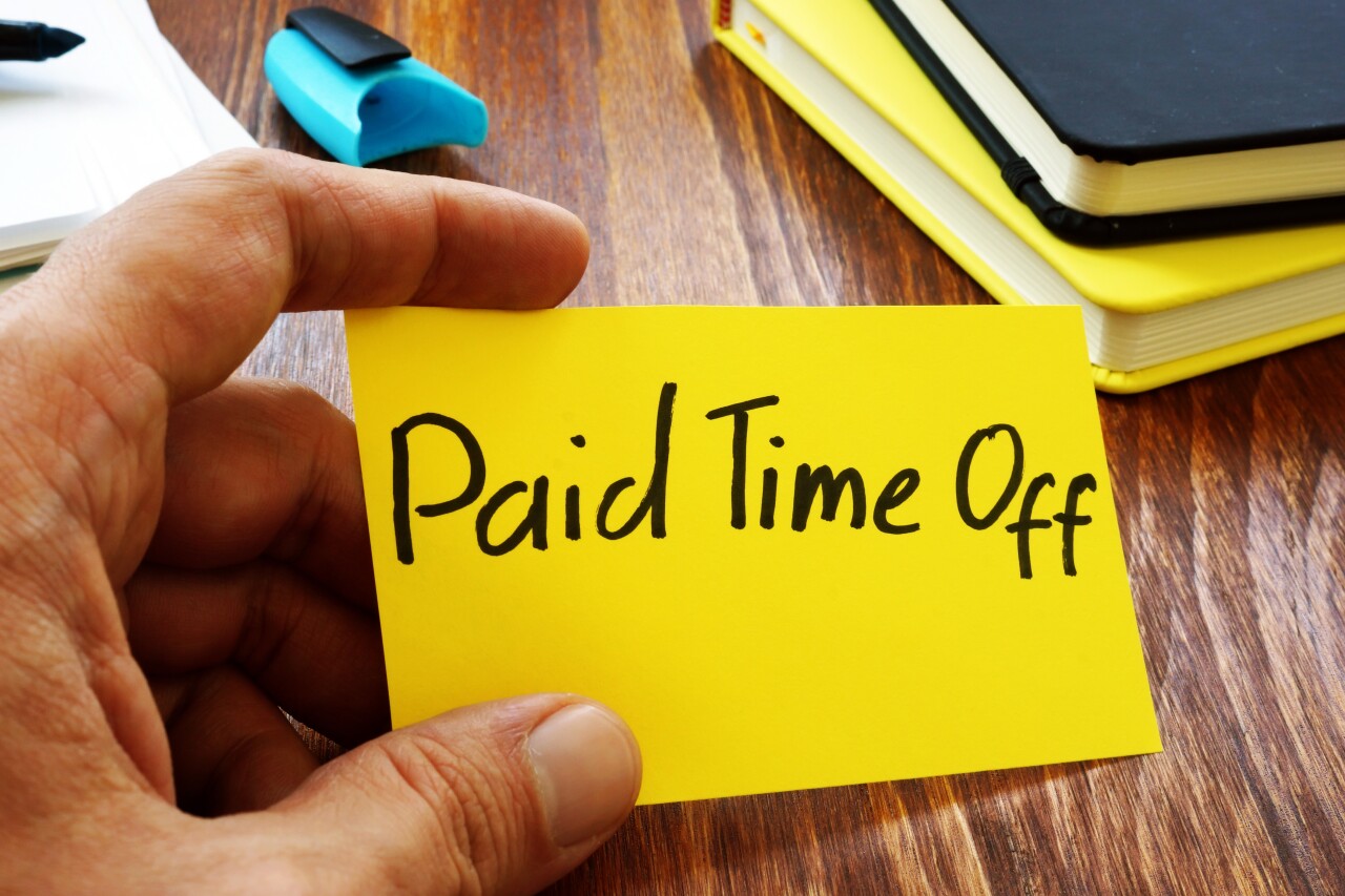 Person holds note card reading "paid time off."