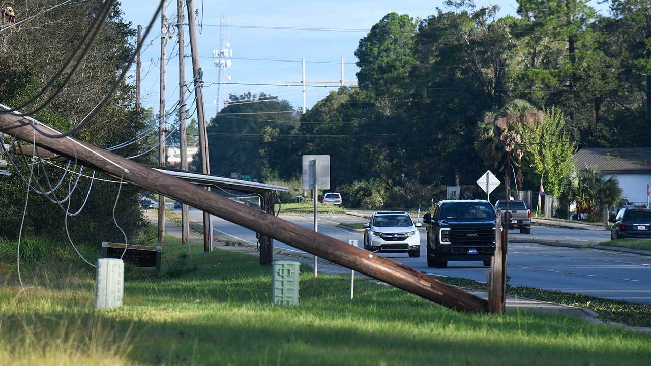 Vehicles pass a utility pole brought down by the effects of Isaias on Saturday, Oct. 10, 2026, in East Milton, Fla.  