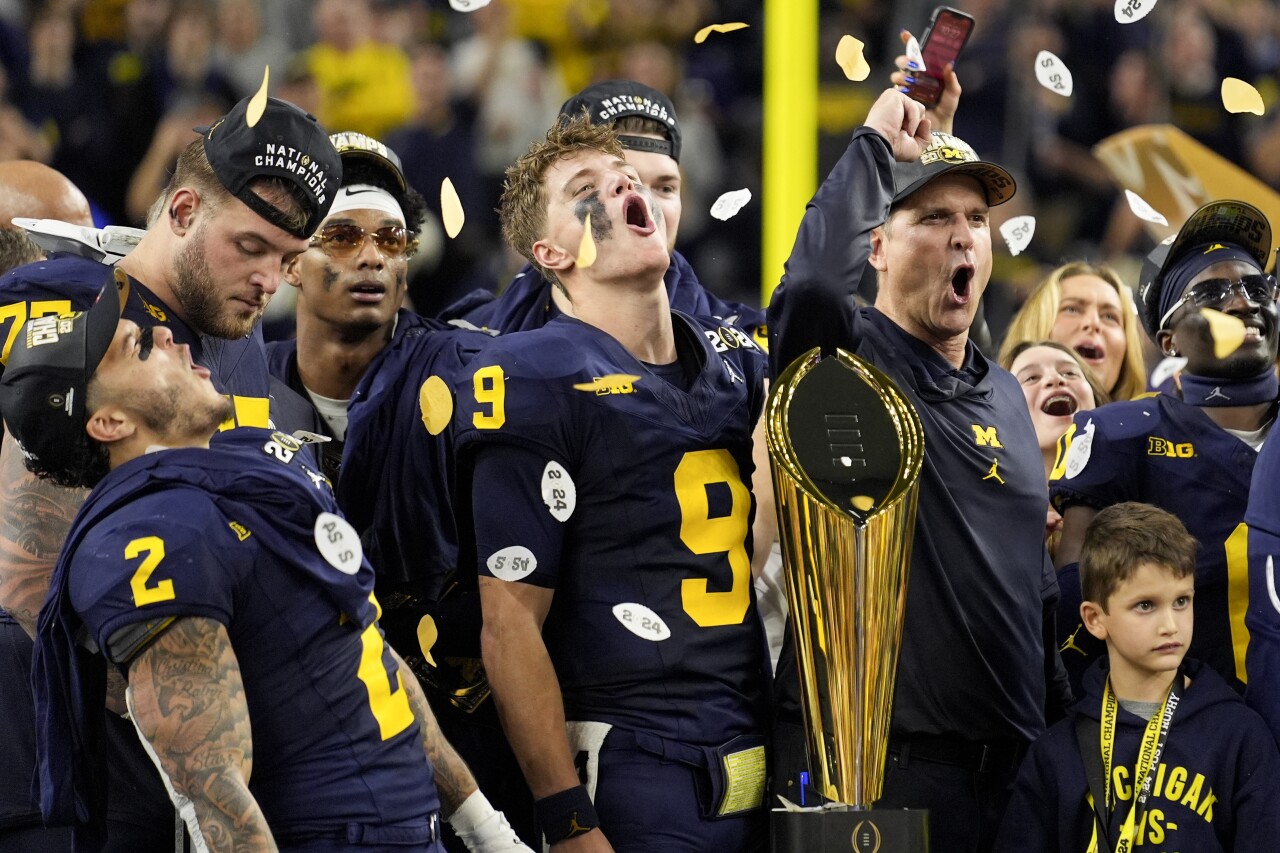 Michigan Wolverines QB JJ McCarthy celebrates with head coach Jim Harbaugh and teammates in front of trophy after winning College Football Playoff National Championship, Jan. 8, 2023