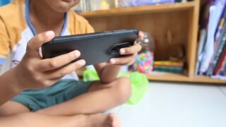 Stock image of a young boy on a mobile device.