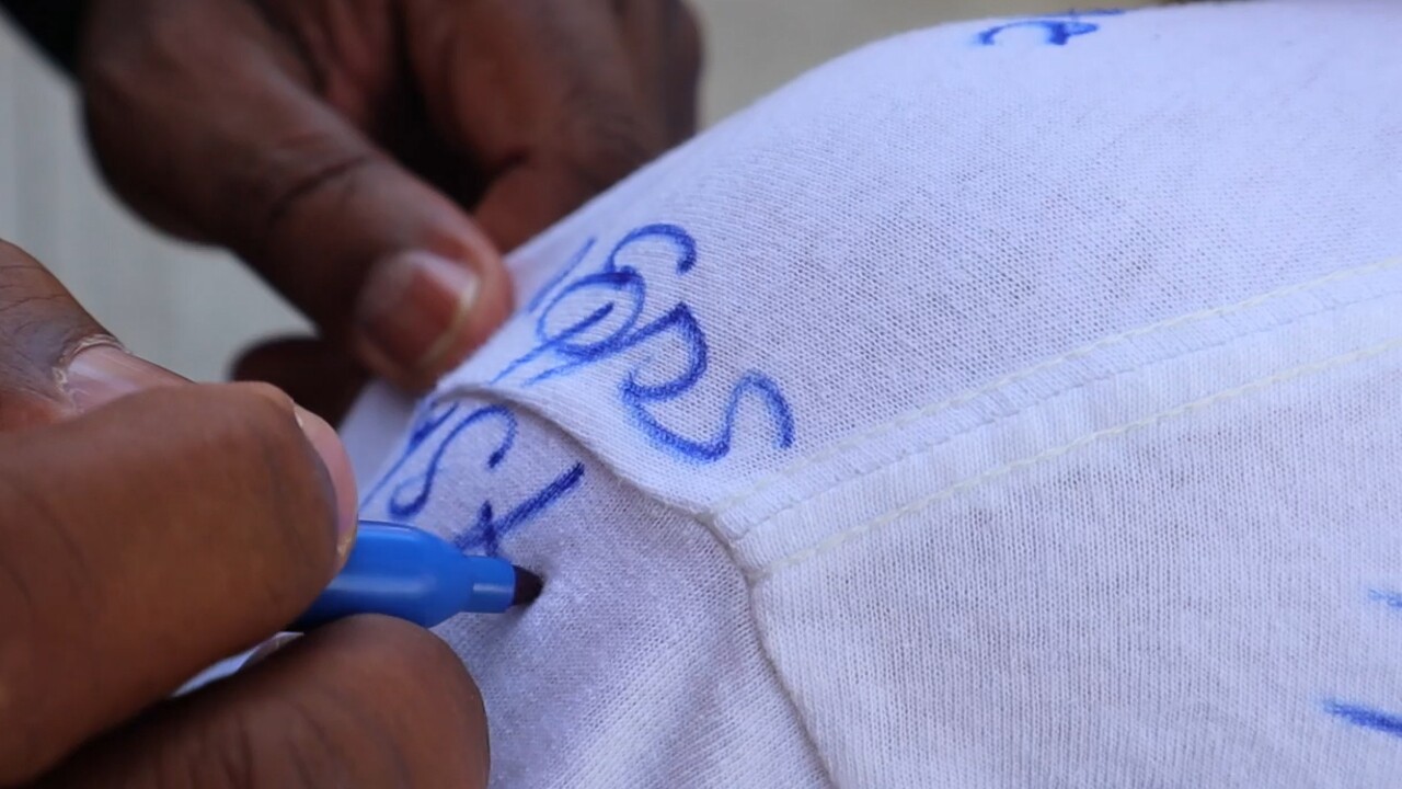 Principal Dr. Elvis Epps from Lake Worth Community High School signs a student's shirt on May 26, 2022.jpg