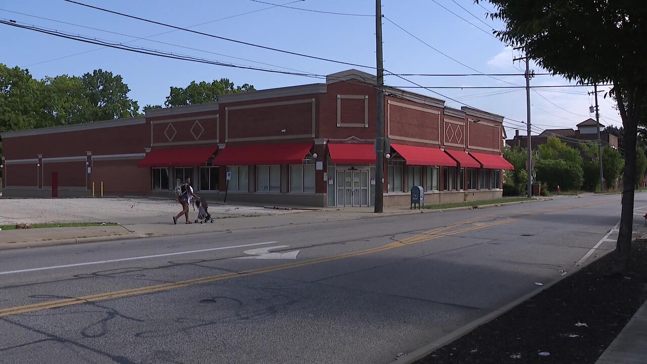 A woman pushes a stroller past the vacant CVS on Madison Avenue in Cleveland.