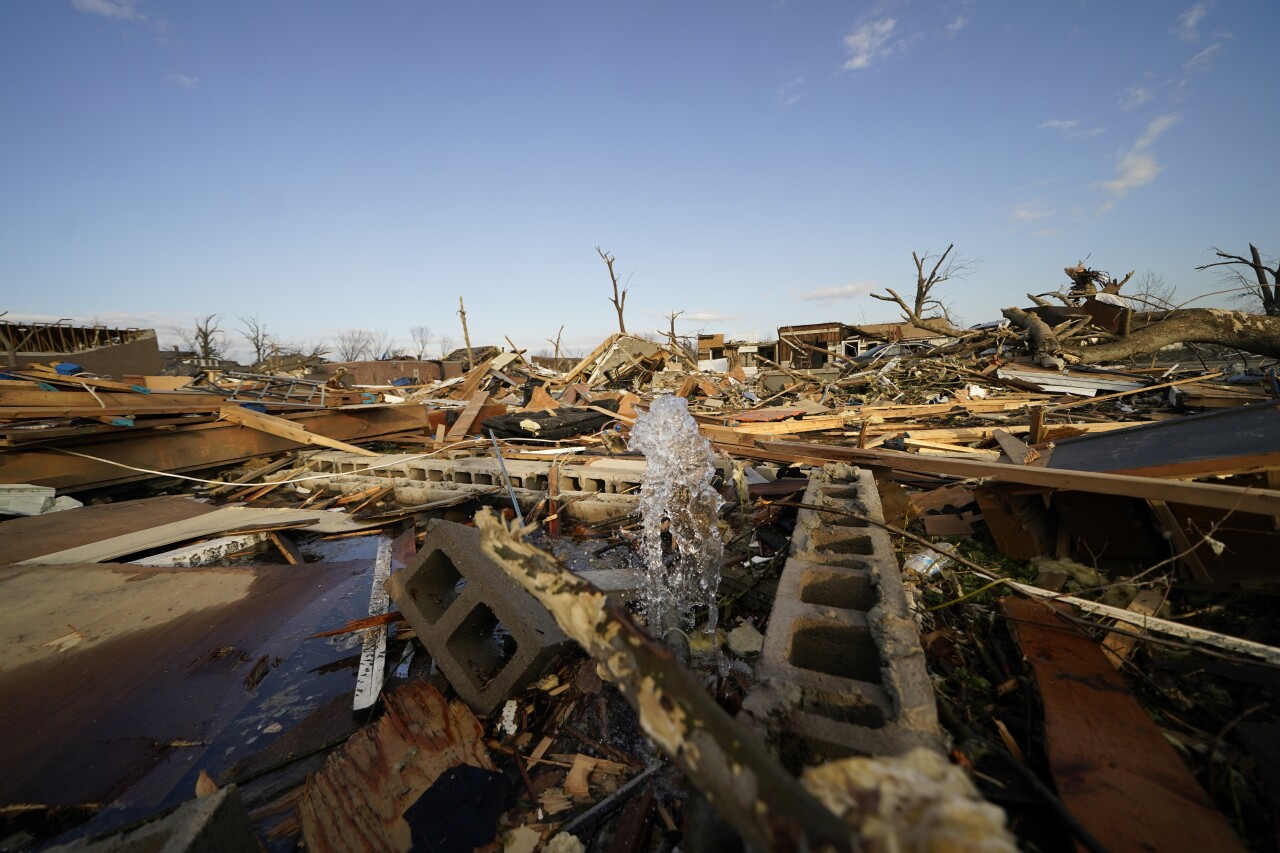 water pipe spews in rubble of homes damaged by tornadoes in Mayfield, Kentucky