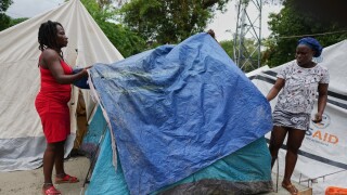 People place plastic tarps over their tents ahead of expected rain at a shelter for families displaced by gang violence in Port-au-Prince, Haiti.