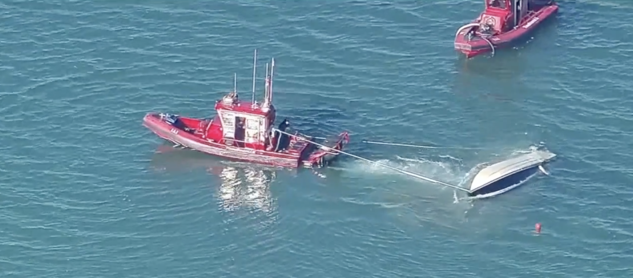 The capsized boat being taken away by first responders