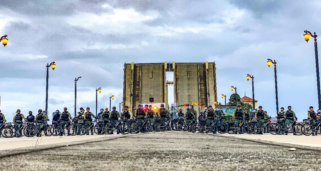 Police and deputies stand guard along the Royal Park Bridge during protest