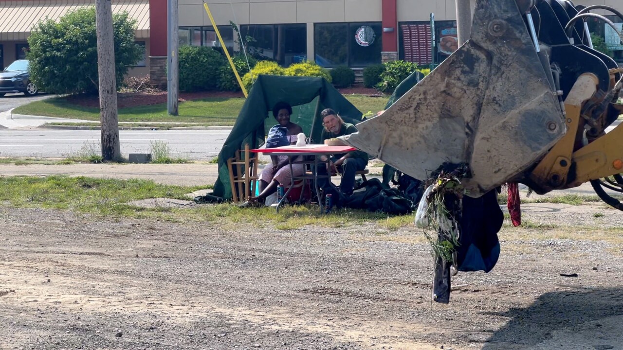 Daniel Strunk and Makwaria Littlejohn look on as city workers tear down homeless encampment