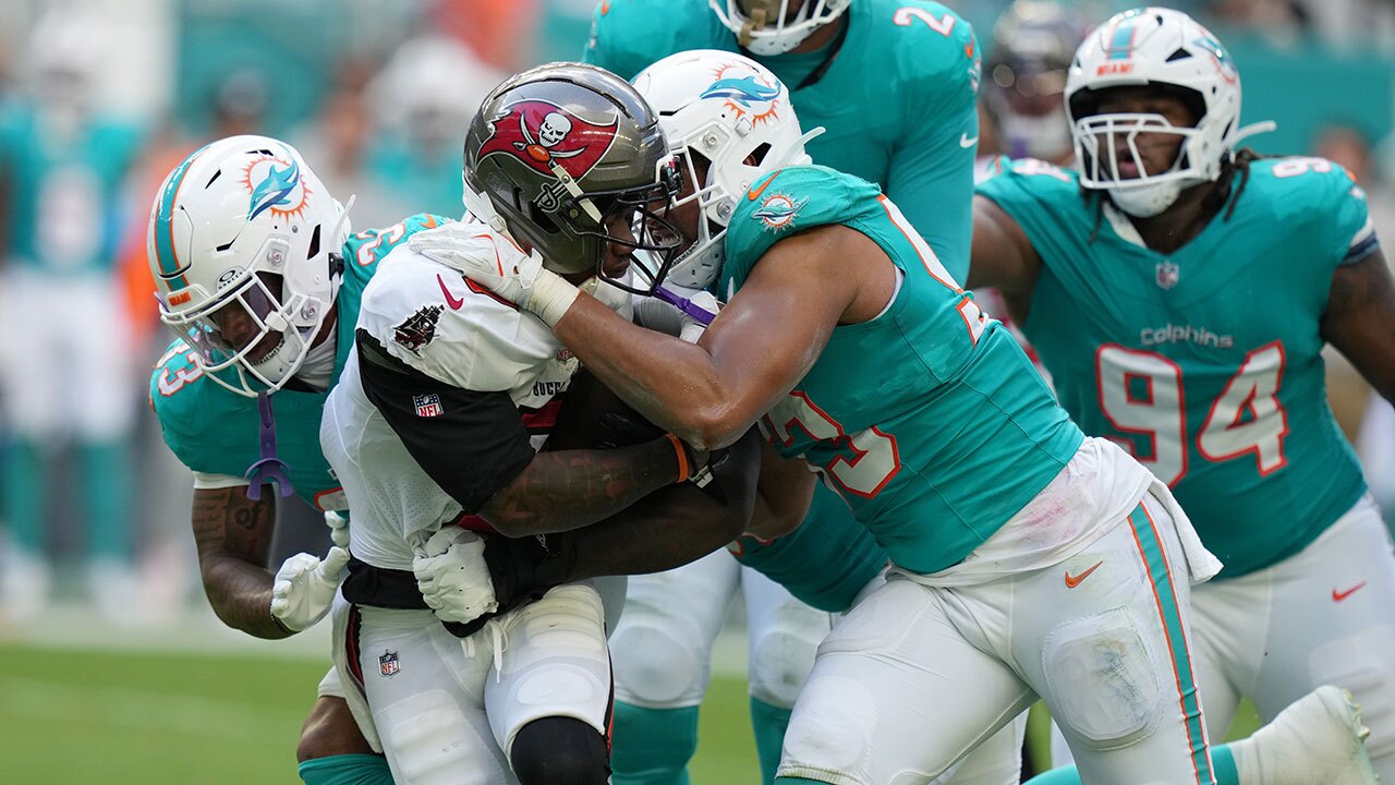 Miami Dolphins defensive tackle Zeek Biggers, front right, and cornerback Jason Marshall Jr. (33) tackle Tampa Bay Buccaneers running back Bucky Irving, second from left, during the first half of an NFL football game Sunday, Dec. 28, 2025, in Miami Gardens, Fla.