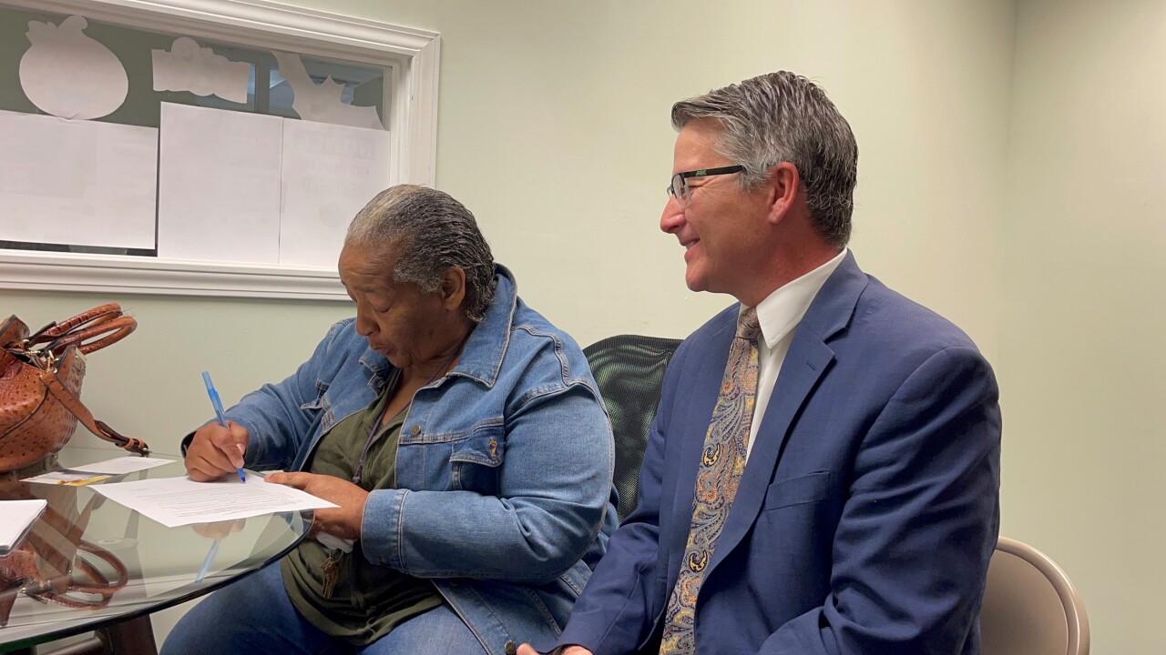 Valerie Lane signs the lease for her new home as Brian Garry looks on.