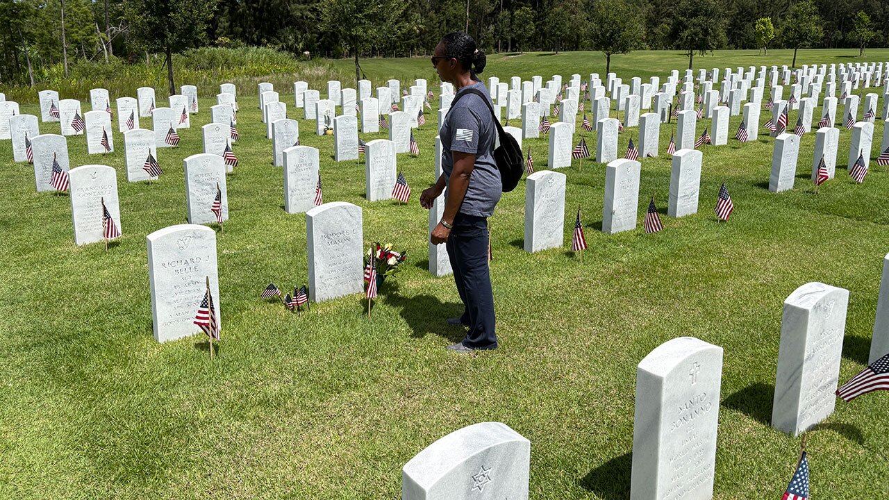Sherry Mason stands at the grave site of her husband at South Florida National Cemetery.