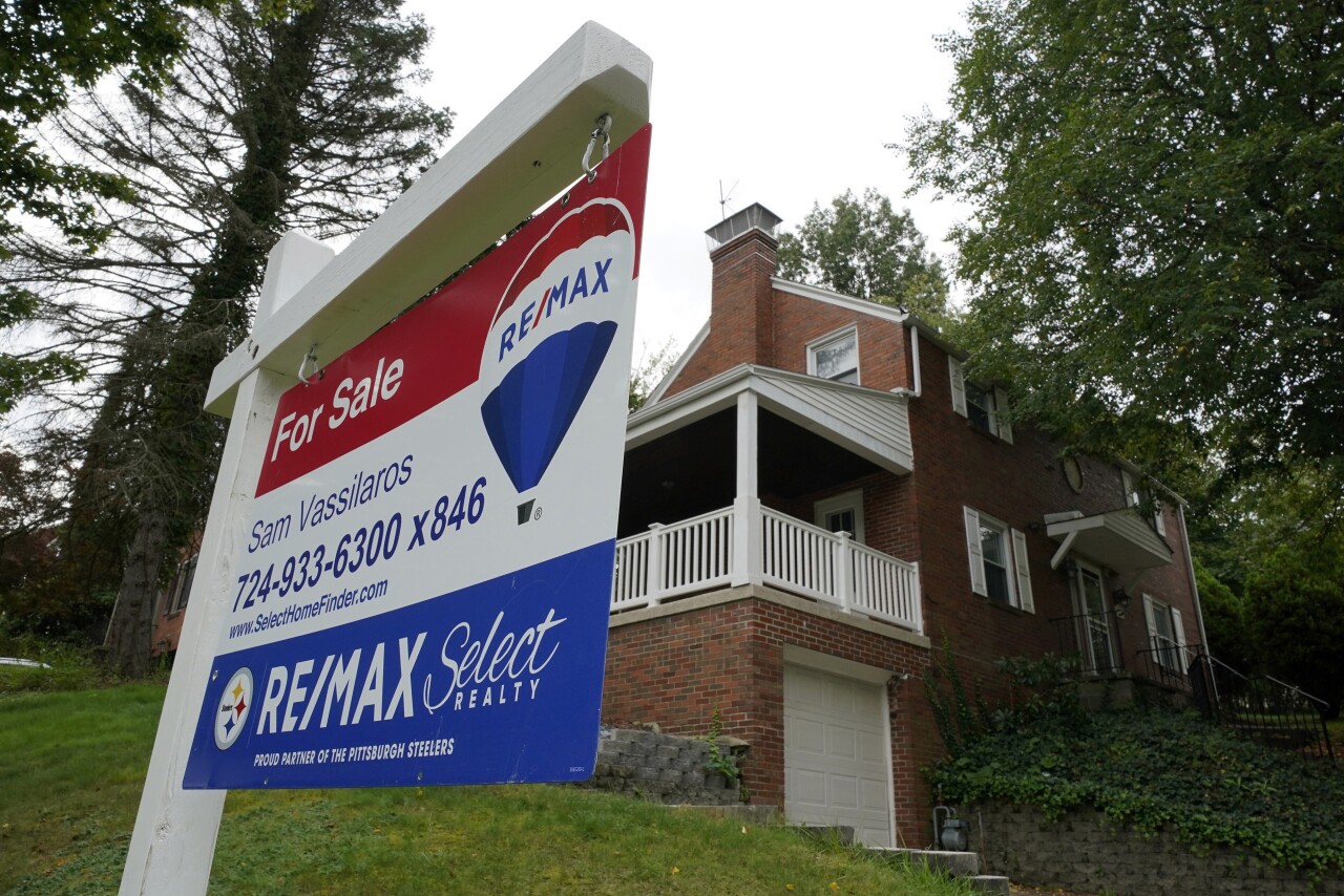 Home for sale sign in the lawn of a residence.