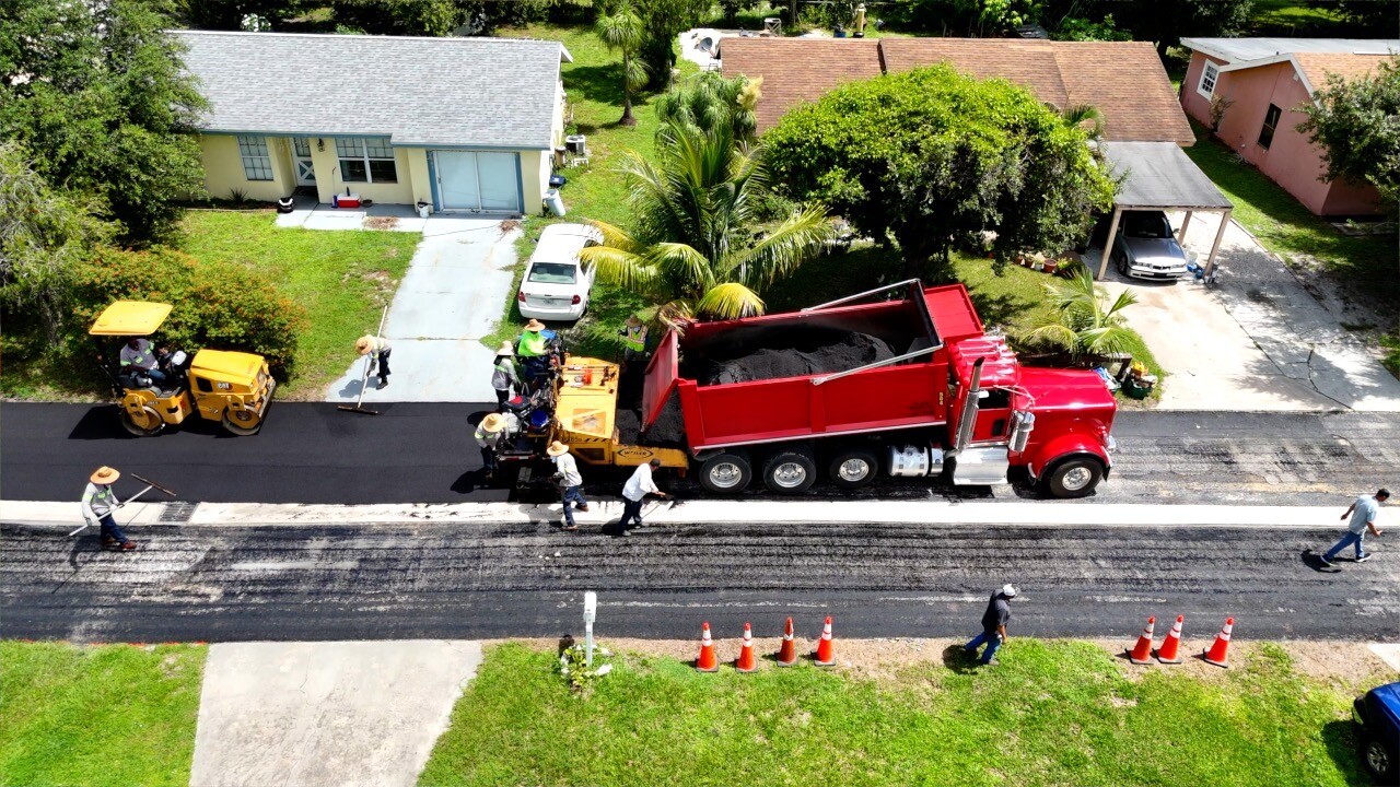 Aerial view of crews hard at work laying fresh asphalt down.