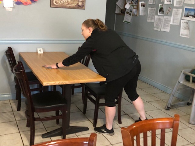 Manager wipes down table and chairs