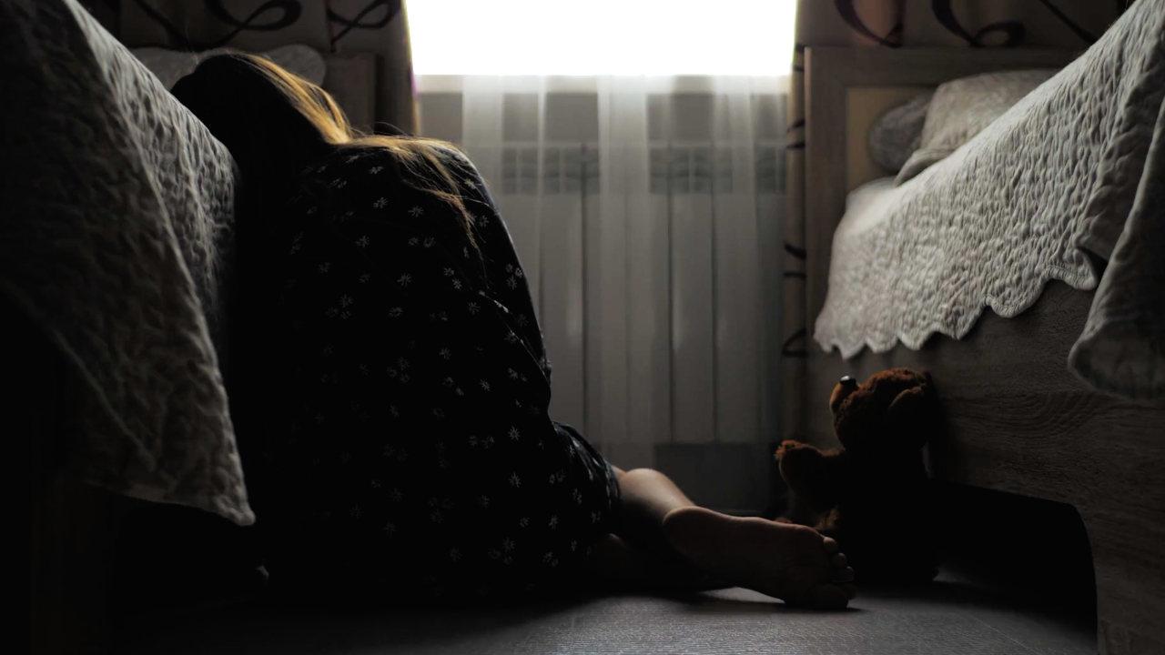 Child looking at window with teddybear