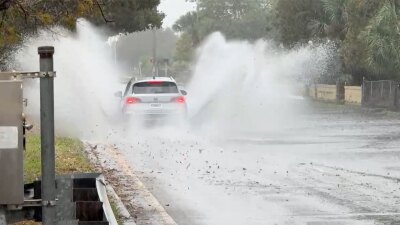 A driver navigates a water-soaked Australian Avenue in West Palm Beach after heavy rains on March 13, 2026.