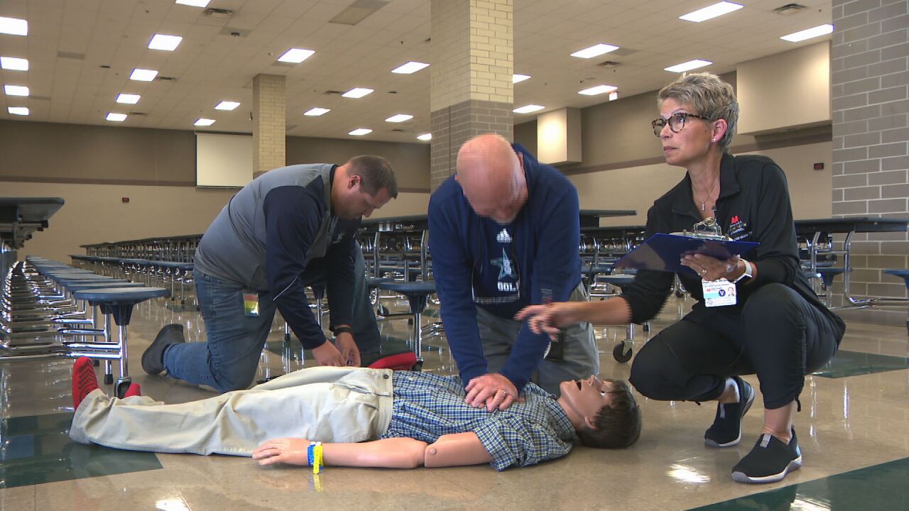 resuscitating CPR dummy in training drill at Siegel High School