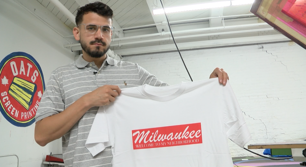 Enrique Murgia holding one of his most known shirts 'Welcome To My Neighborhood.'