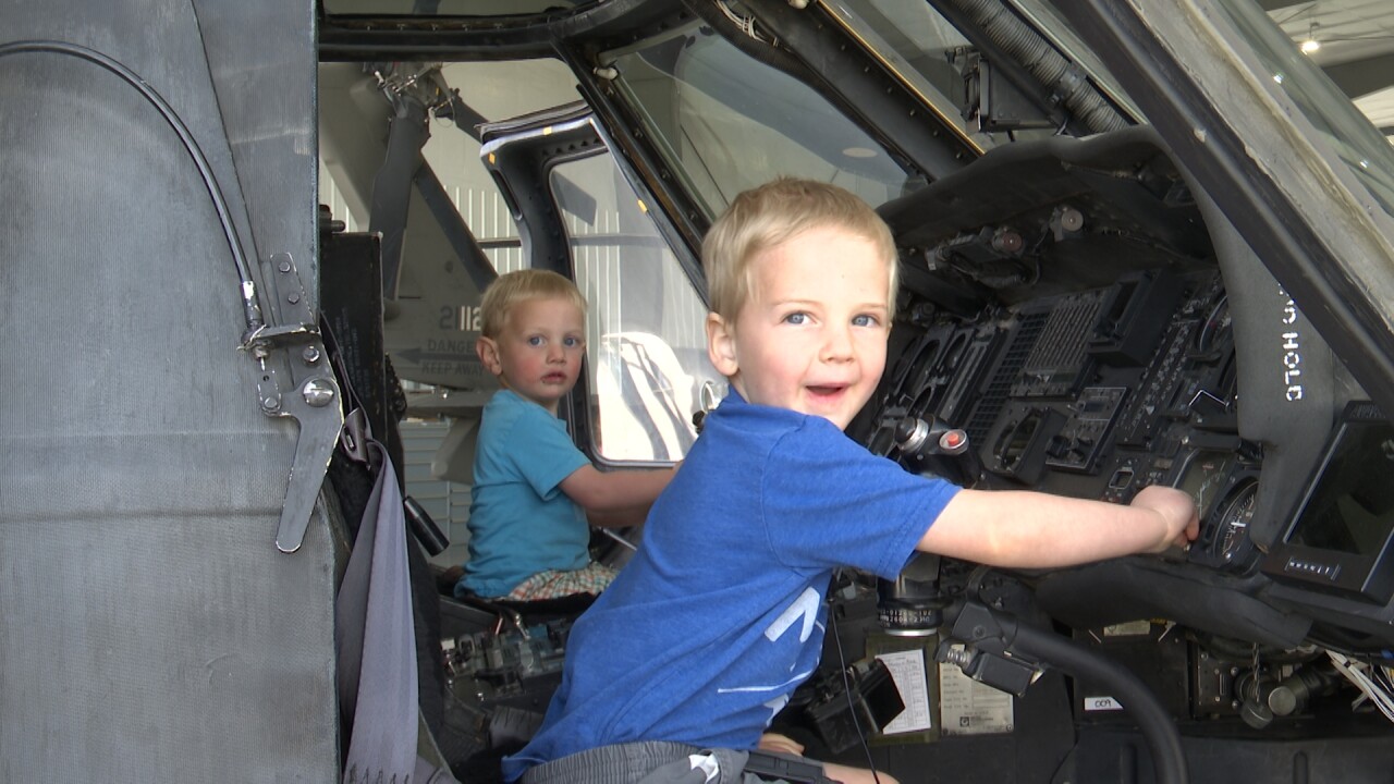 Two young boys sit in a helicopter at open house