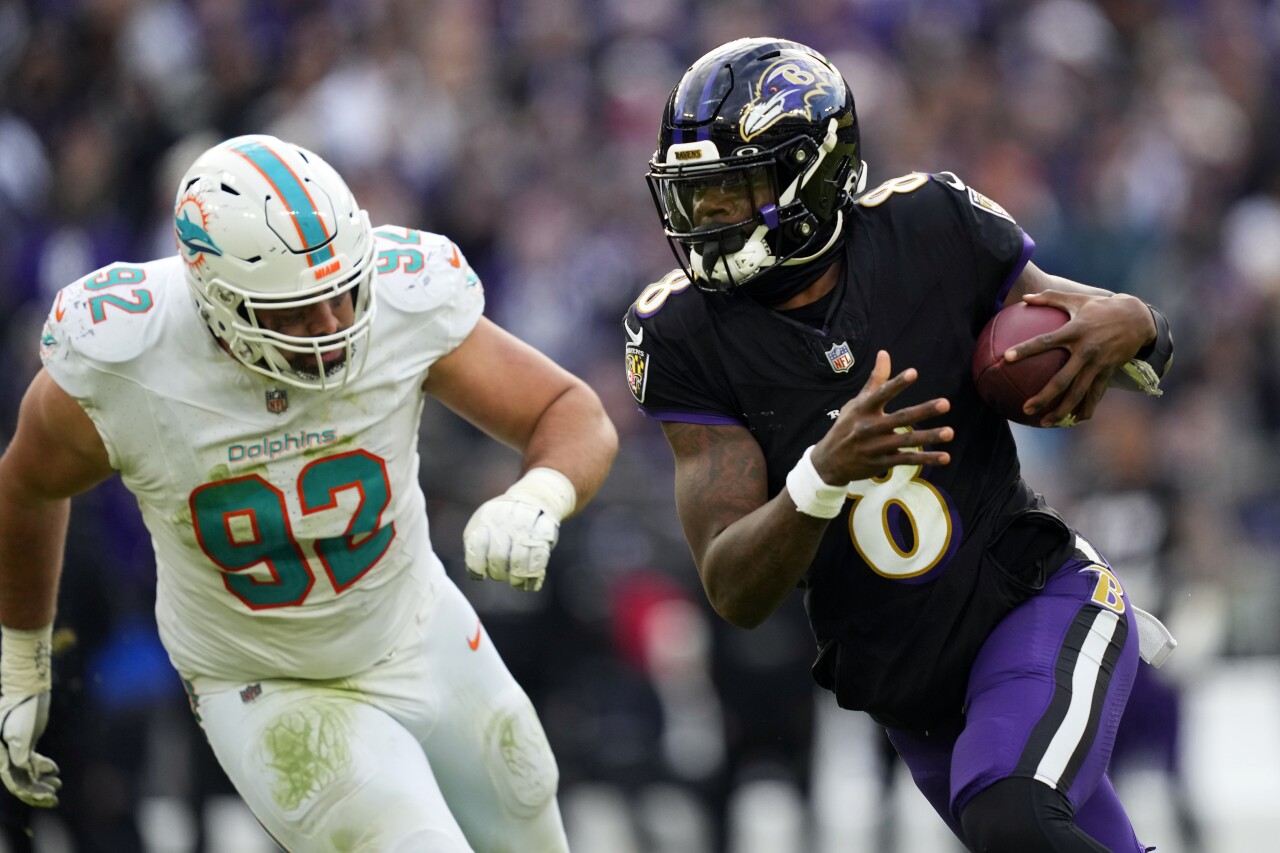 Baltimore Ravens QB Lamar Jackson runs past Miami Dolphins defensive tackle Zach Sieler, Dec. 31, 2023
