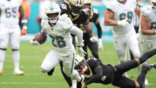 Miami Dolphins running back De'Von Achane (28) escapes a tackle by New Orleans Saints cornerback Alontae Taylor (1) during the first half of an NFL football game Sunday, Nov. 30, 2025, in Miami Gardens, Fla. (AP Photo/Rebecca Blackwell)