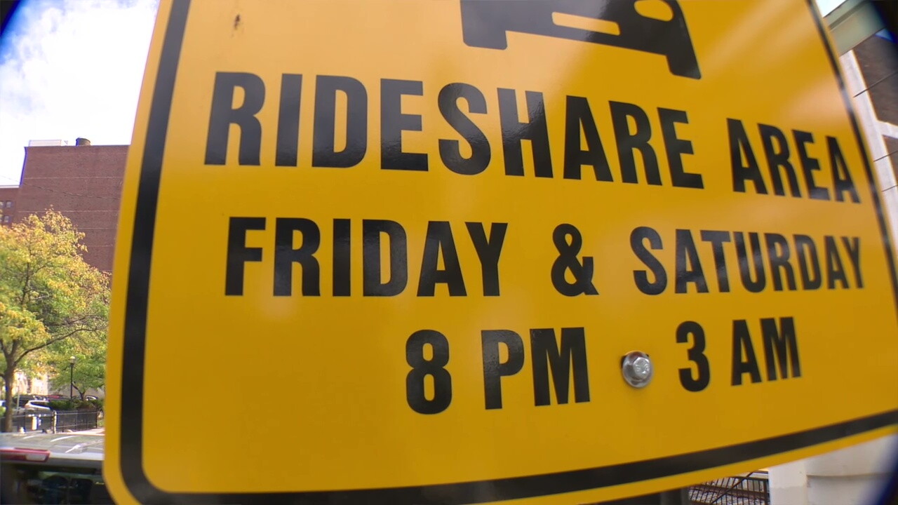 A sign on West 10th Street identifies a designated rideshare pick-up point for the Flats East Bank district.