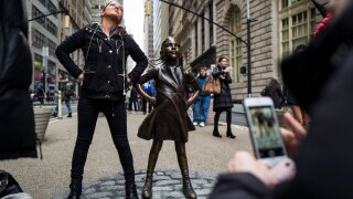 Woman poses beside "Fearless Girl" statue