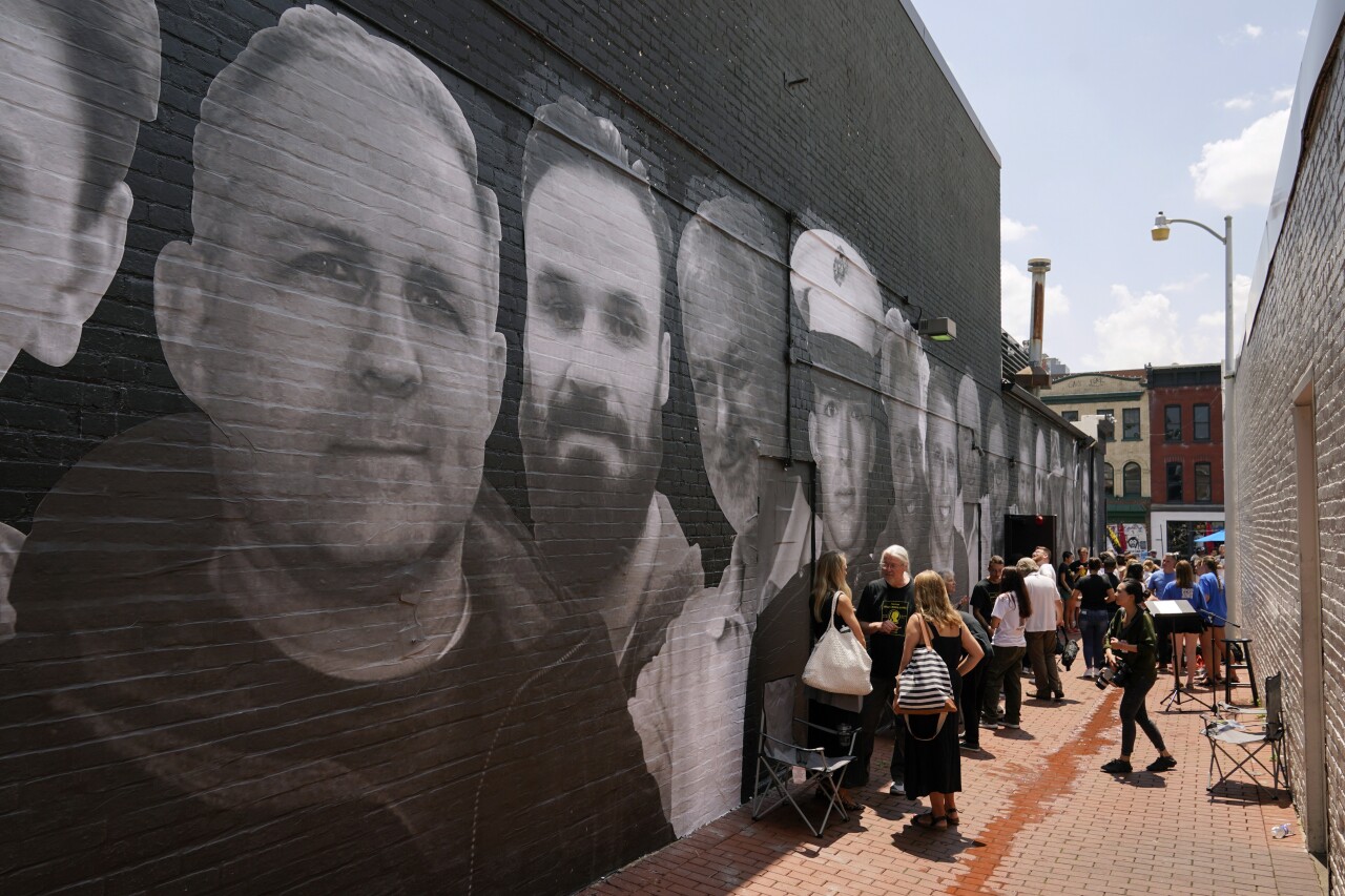 People gather in an alley emblazoned with a mural depicting American hostages and wrongful detainees who are being held abroad, Wednesday, July 20, 2022, in the Georgetown neighborhood of Washington. Pictured at top left is U.S. Marine Corps veteran and Russian prisoner Paul Whelan. (AP Photo/Patrick Semansky)