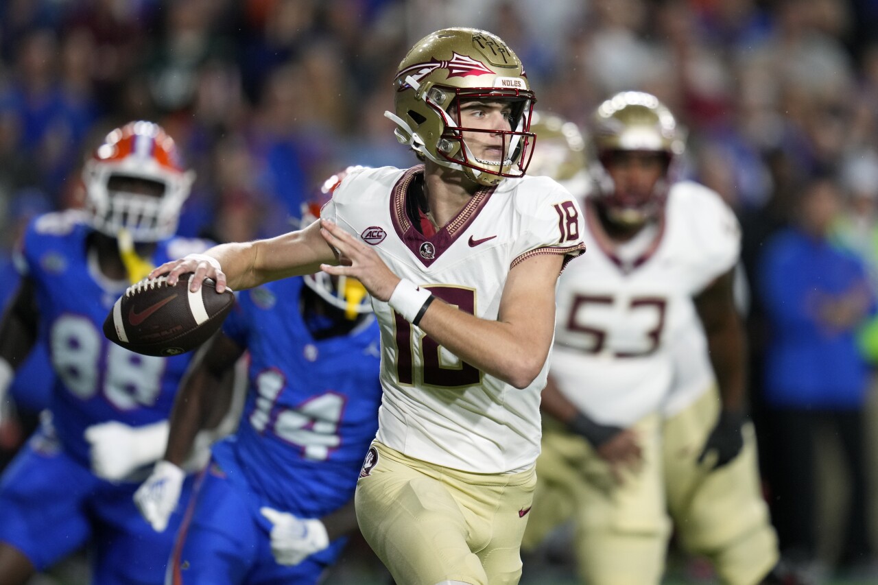 Florida State Seminoles QB Tate Rodemaker looks for receiver as he is pressured by Florida Gators safety Jordan Castell and defensive lineman Caleb Banks during first half, Nov. 25, 2023