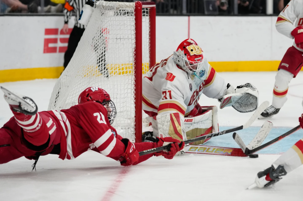 Wisconsin forward Ryan Botterill (21) dives to attempt a shot on Denver goaltender Johnny Hicks (31) in the second period of the championship game at the NCAA Frozen Four men's college hockey tournament Saturday, April 11, 2026, in Las Vegas.