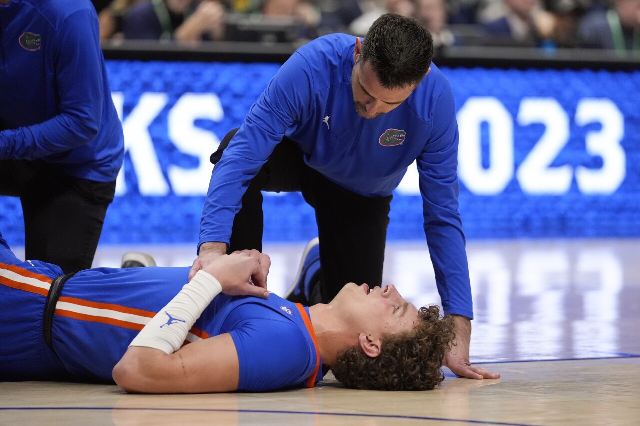 Florida Gators basketball coach Todd Golden kneels next to center Micah Handlogten after his injury in first half of SEC Tournament final, March 17, 2024
