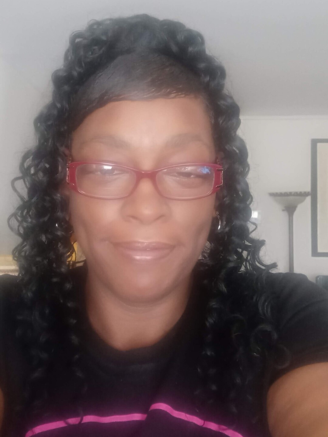 Tara Andrews is smiling in this undated photo. She has long, dark curly hair and glasses with red frames.