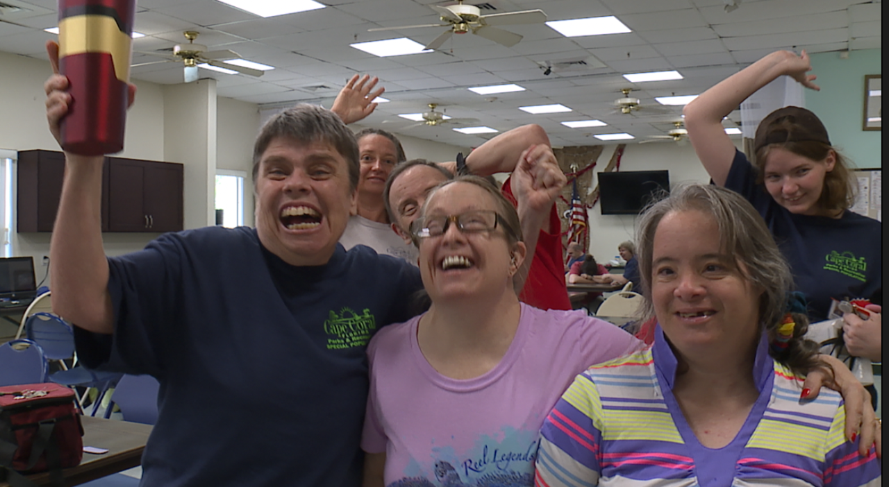 Attendees of the Smith Special Populations Center in Cape Coral smile during a ribbon cutting for their new koi pond