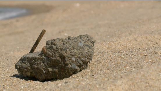 A rock sits in the sand in East Beach.