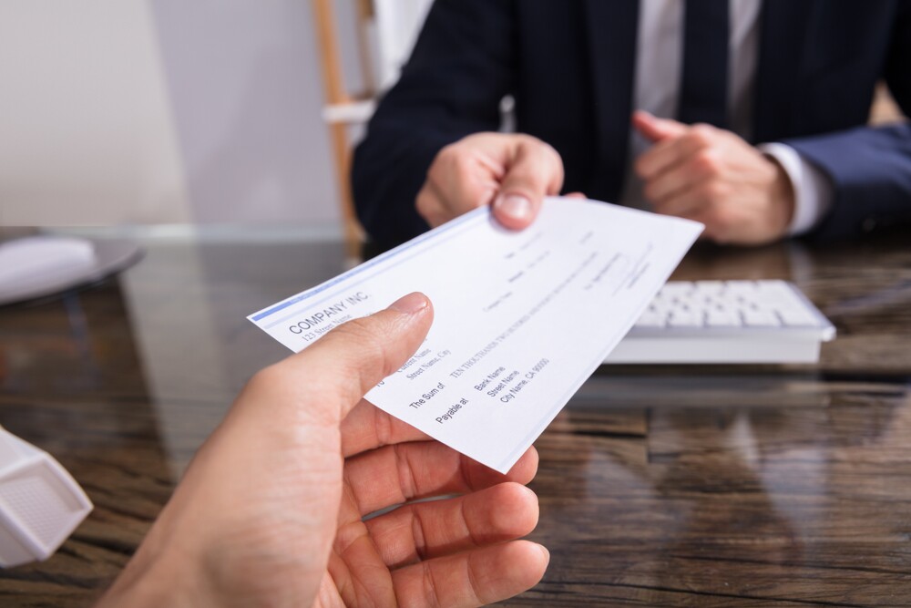 A businessperson giving a paycheck to someone.