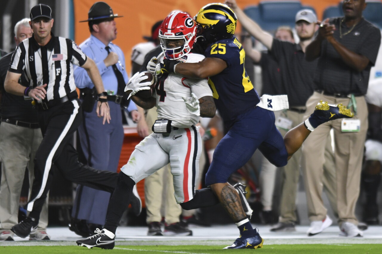 Georgia Bulldogs running back James Cook tackled by Michigan Wolverines linebacker Junior Colson in College Football Playoff semifinal at Orange Bowl