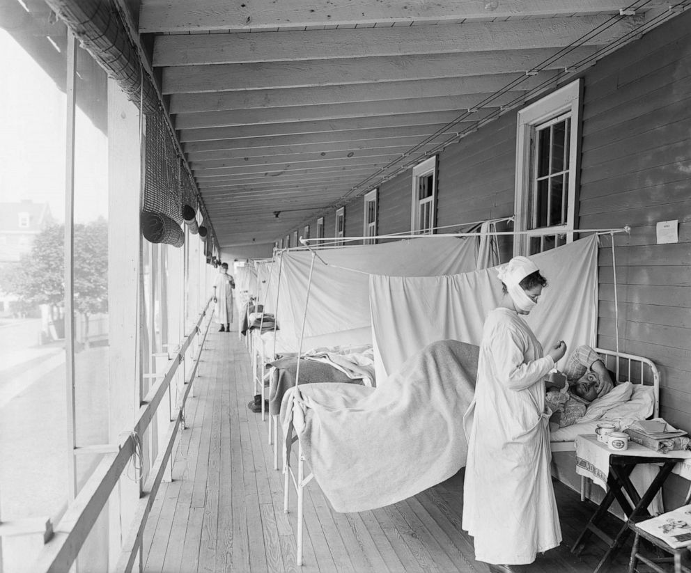 Universal Images Group via Getty Images
A masked nurse at the head of a row of beds treats patients during the influenza pandemic at Walter Reed Hospital, in Washington D.C., 1918.