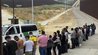Migrants seeking asylum line up while waiting to be processed after crossing the border