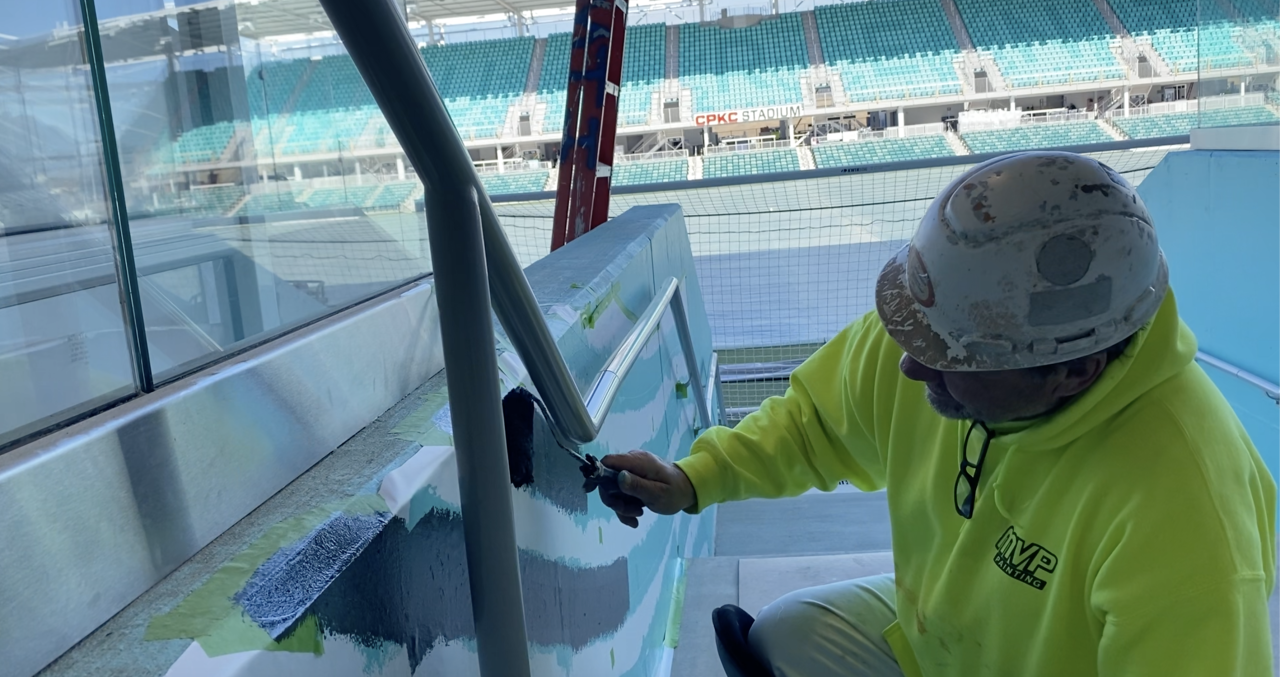 Andy Bower painting murals at CPKC Stadium