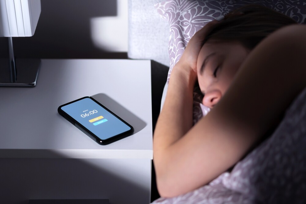 Phone alarm on a table next to a sleeping woman.