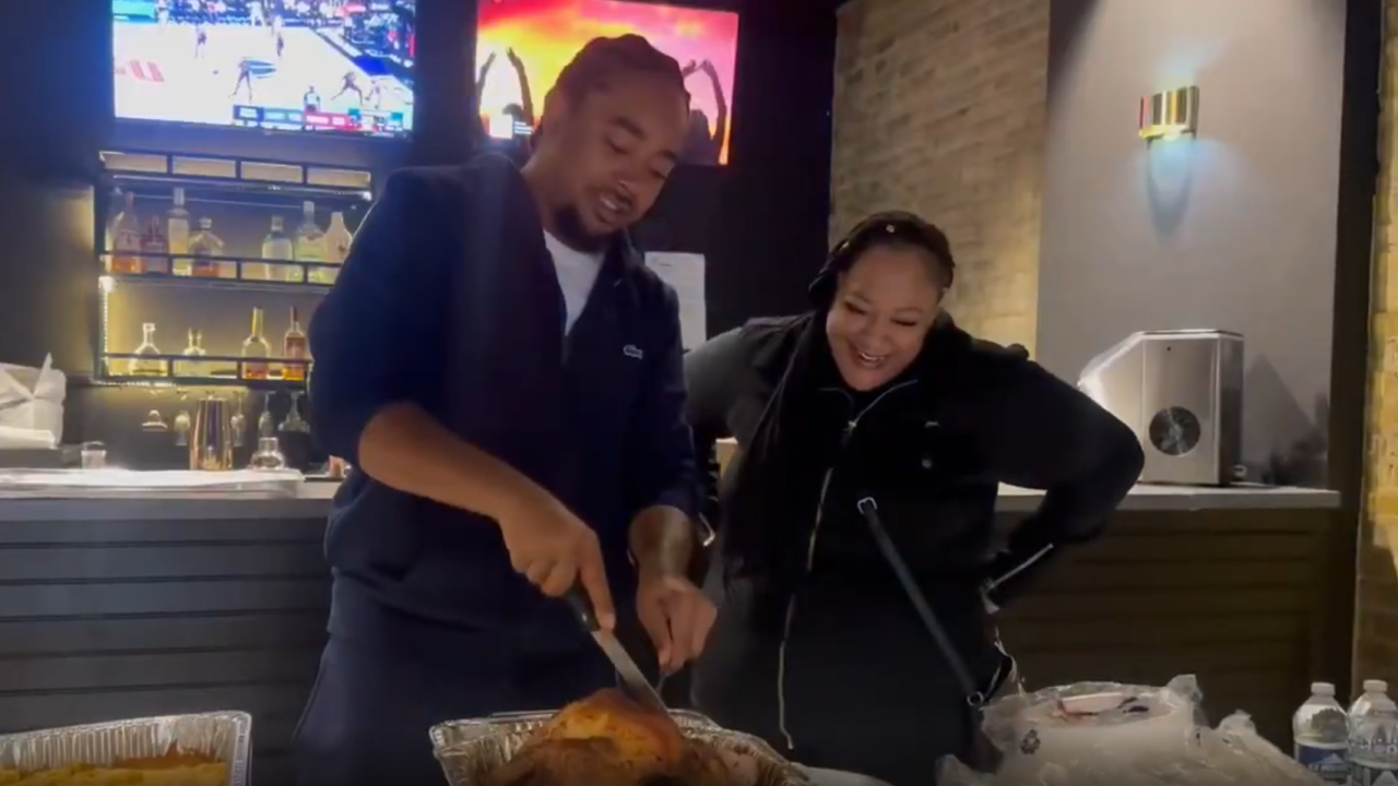 Dontay White (left) cuts into a turkey during a free Thanksgiving meal giveaway at King's Kitchen & Cocktails on Saturday, Nov. 22, 2025 in Racine.