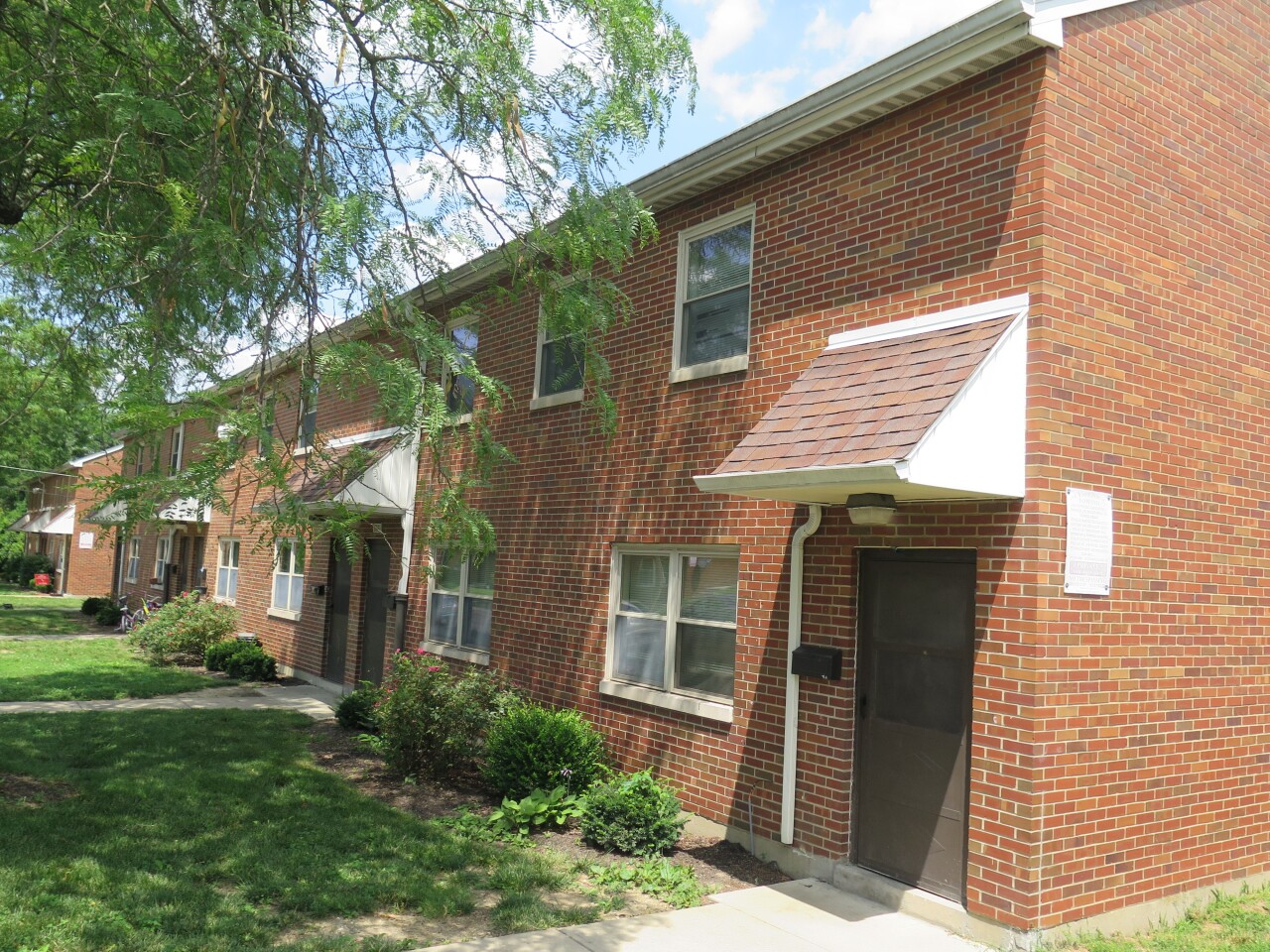 This photo shows a group of homes at Marianna Terrace in Lincoln Heights as they currently look. The buildings are red brick, and each door has a small awning above it.